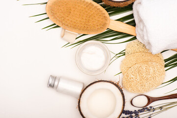 Fototapeta na wymiar top view of sponges, massage brush, cosmetic cream, lotion and towel near palm leaves on white, stock image