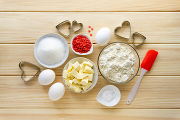 Step by step recipe of making cookies for valentine's day. Baking ingredients and kitchen utensils on wooden background