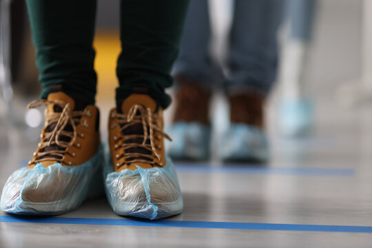 People Standing In Line In Shoe Covers At Clinic Closeup. Rules Of Conduct During The Covid 19 Pandemic Concept