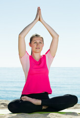 Fototapeta na wymiar Smiling girl practicing various yoga poses during training on beach