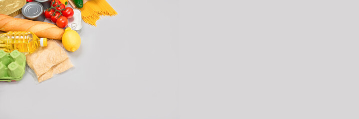 Banner with flat lay composition - food donations on grey background with copyspace - pasta, fresh vegatables, canned food, baguette, cooking oil. Food donation or food bank concept