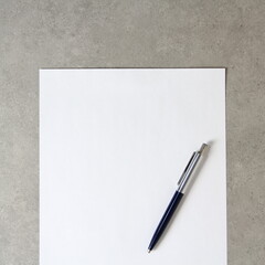 Template of white paper with a ballpoint pen on light grey concrete background. Concept of new idea, business plan and strategy, empty space for text