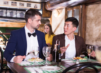 Two men are dinning in luxury restaurante together indoor.