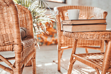 Comfortable living room for solitude and relaxation in daytime with bamboo chairs and table with books and coffee cup on it.