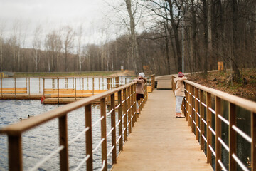 Children girls sisters run walk along wooden paths in an autumn park
