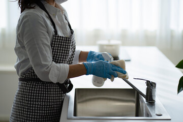 消毒液でキッチンを掃除する女性