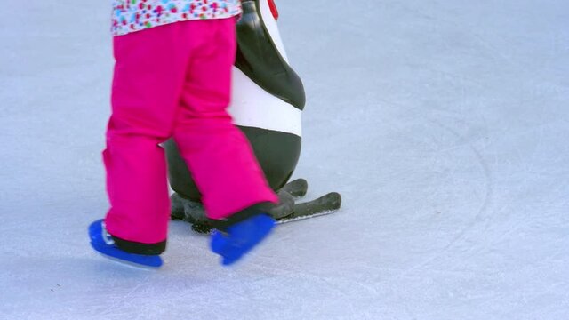 Close up on kids learning ice skating on artificial ice rink.