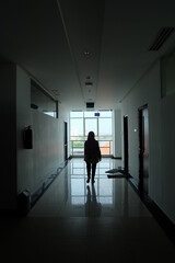 Fototapeta na wymiar silhouette of a woman walking in dark corridor