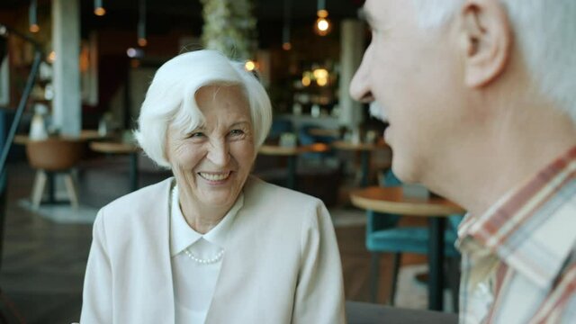 Happy senior people man and woman are talking and gesturing enjoying communication during lunch indoors in restaurant. Conversation and family concept.