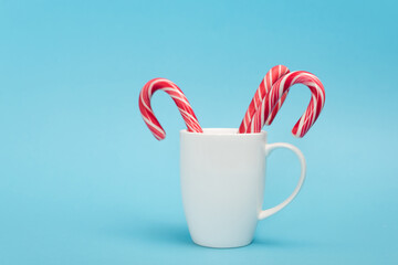 candy canes in white mug on blue 