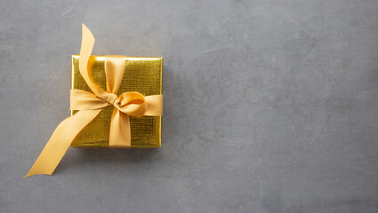 Golden gift box on gray background with copy space, Merry christmas greeting card, birthday and new year concept