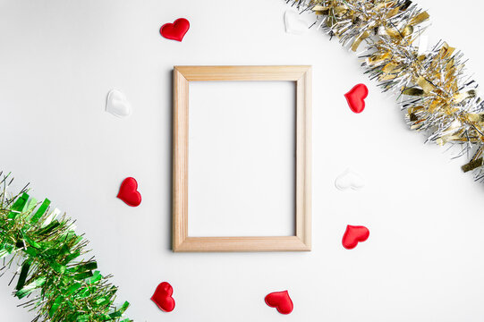 Wooden frame mockup with decorative red and white hearts with gold and green Christmas tinsel around the edges. Idea for text, photos. Your photos are framed with beautiful and festive decorations