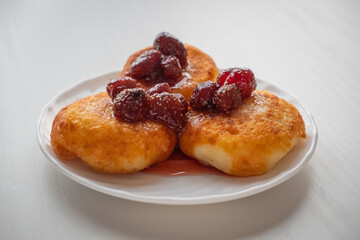 Russian syrniki or cheesecakes poured with strawberry jam close up