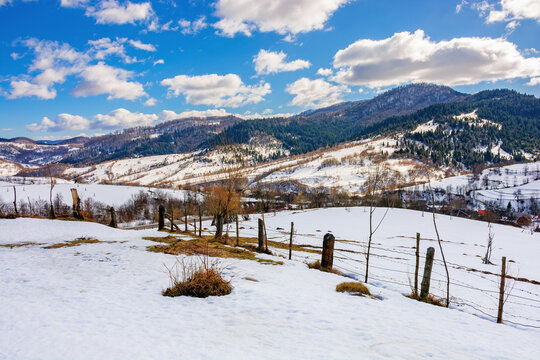 mountainous rural landscape on a sunny winter day. fields and trees on rolling hills covered in snow. fluffy clouds on the sky. beautiful carpathian landscape