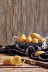 Raw potato and knife on wooden table