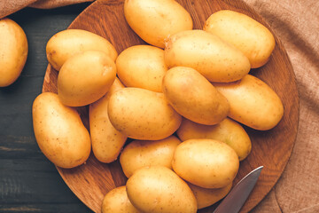 Plate with raw potatoes on wooden table