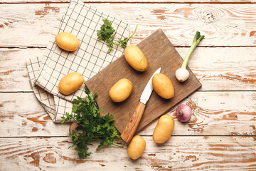 Fototapeta premium Raw potatoes with knife and cutting board on wooden table