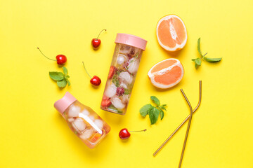 Fototapeta na wymiar Bottles of infused water with citruses and berries on color background