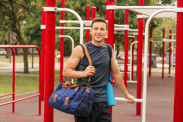 Young man with bag on sport ground