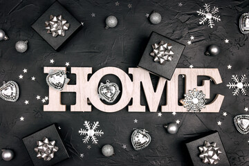 Stay home for the Christmas holidays. The words Home surrounded by silver festive decorations on a black background.