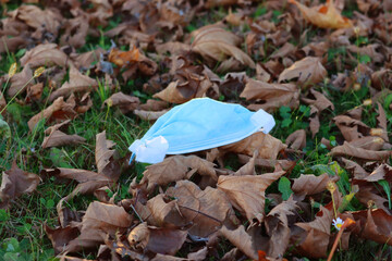 Waste during Covid-19. Medical protective face mask on green grass 