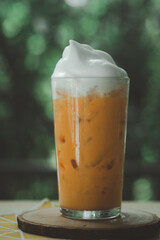 A glass of Thai milk tea with milk foam on top