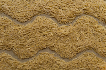 Two wavy lines among finely chopped uncooked noodles scattered on linen canvas