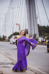 Naklejka premium Young european woman with short hair in purple traditional saree. Outdoor portrait. India, Bangalore