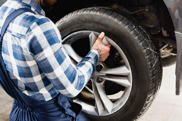 partial view of technician fixing car wheel in workshop, stock image