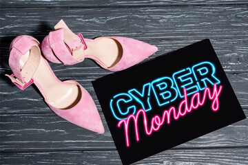 top of pink shoes near placard with neon cyber monday lettering on wooden surface