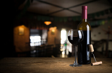 Pouring red wine into the glass against wooden background