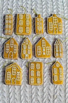 Gingerbread houses with golden ropes to decorate the Christmas tree on a knitted surface