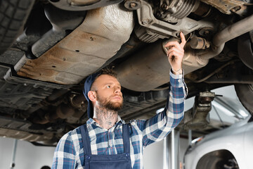  repairman making diagnostic of raised car from bottom