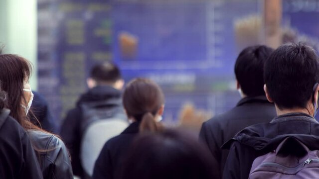 マスクをして出勤する日本人ビジネスマンと株価ボード電光掲示板