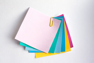 Multi-colored note sheets connected with a yellow paper clip