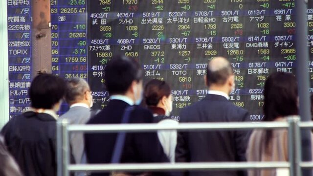 マスクをして出勤する日本人ビジネスマンと株価ボード電光掲示板