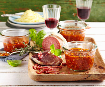 Bolognese sauce in preserving jars served with Parma ham and salami
