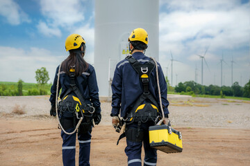 Asian man and woman Inspection engineers preparing and progress check of a wind turbine with safety in wind farm in Thailand. © ake1150