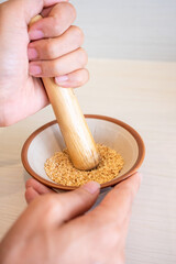 Japanese sesame grinding bowl and wooden stick. Wooden bowl with white sesame for grinding on wooden table.