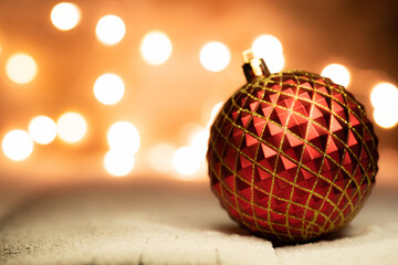Christmas balls on snowy wooden table with christmas lights on background. Selective focus. Shallow depth of field.