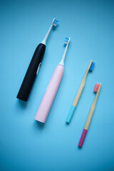 ultrasonic electric and bamboo toothbrushes on a blue background