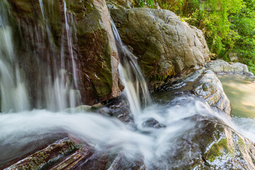 Obraz premium Long exposure photo of a small waterfall or water stream with a big rocks