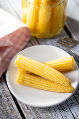 Pickled young baby corn cobs on plate.