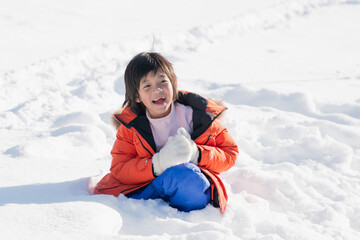 Fototapeta na wymiar Asian child wearing winter clothes playing on snow in the park