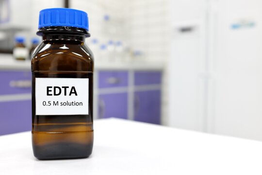 Selective focus of EDTA liquid chemical compound reagent solution in dark glass bottle inside a chemistry laboratory with copy space.