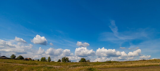 White clouds in blue sky over grass field in summer