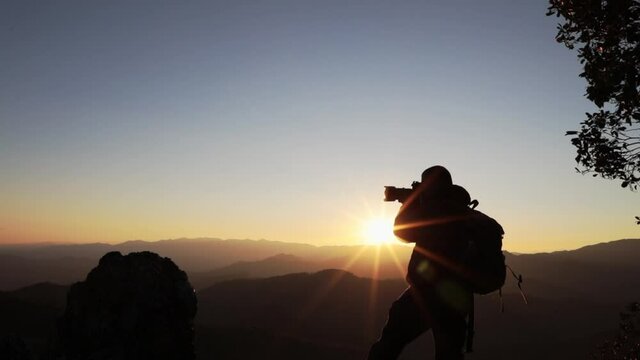 Nature photographer take photos with mirror camera on peak of mountain.