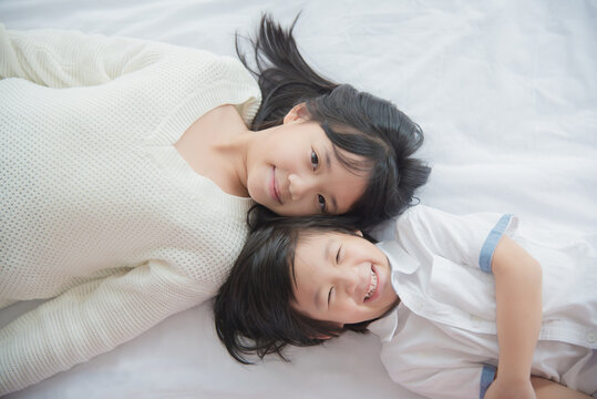 Cute asian children lying on white bed