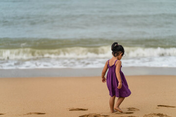 Cute little girl playing on the beach in morning.