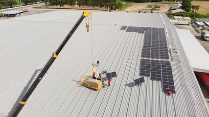 Solar panels installed on a roof of a large industrial building or a warehouse. Industrial buildings in the background. Horizontal photo.